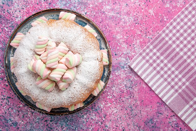 Draufsicht des Zuckerpulverkuchens mit Marshmallows auf rosa Oberfläche