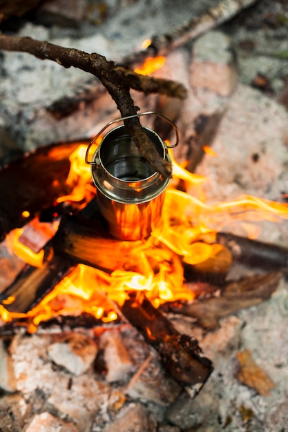 Kostenloses Foto draufsicht, die das wasser über einem lagerfeuer erhitzt