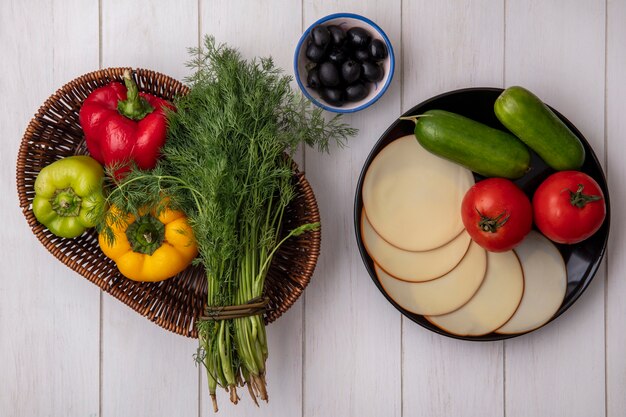 Draufsicht Dill mit Paprika in einem Korb mit geräucherten Käsetomaten und Gurken mit Oliven auf einem weißen Hintergrund