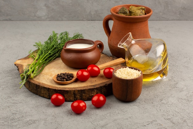 Draufsicht Dolma im Topf zusammen mit Olivenöl der roten Kirschtomaten und Joghurt auf dem grauen Boden