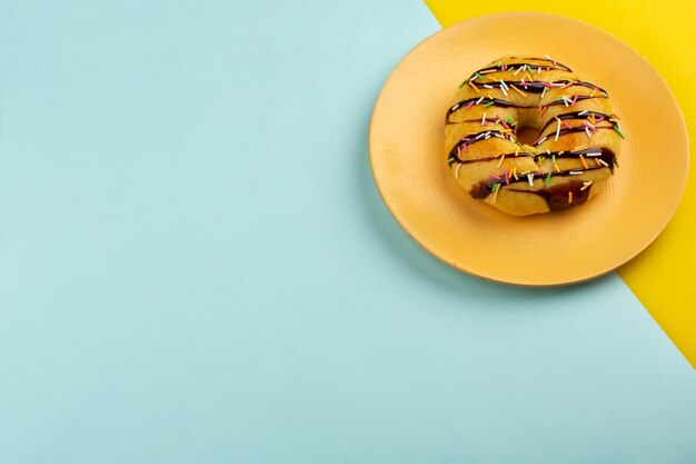 Draufsicht Donut in orange Platte auf dem bunten