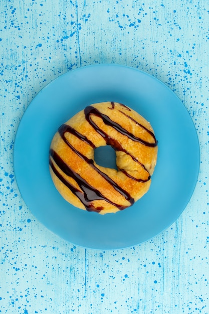 Draufsicht Donut süße leckere runde Schoko innerhalb der blauen Platte auf dem hellen Blau ausgekleidet