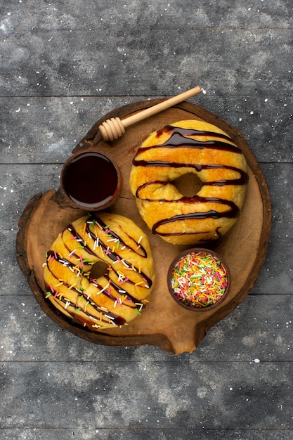 Kostenloses Foto draufsicht donuts mit schokolade lecker lecker auf dem dunklen schreibtisch