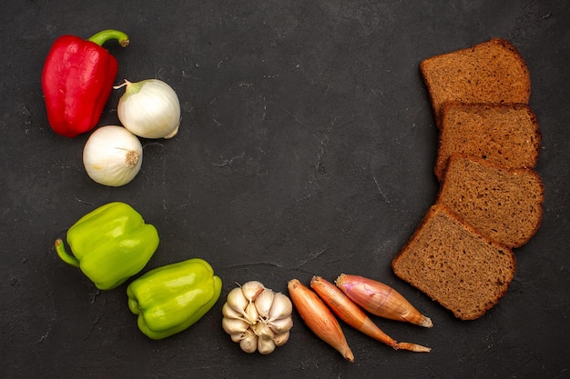 Draufsicht dunkle Brotlaibe mit Gemüse auf dunklem Raum