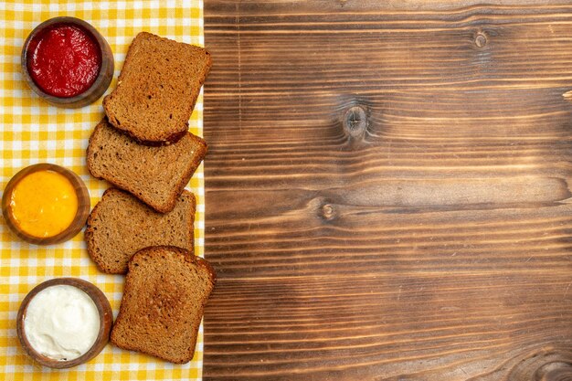 Draufsicht dunkle Brotlaibe mit Gewürzen auf braunem Holztischbrot würzige Gewürze