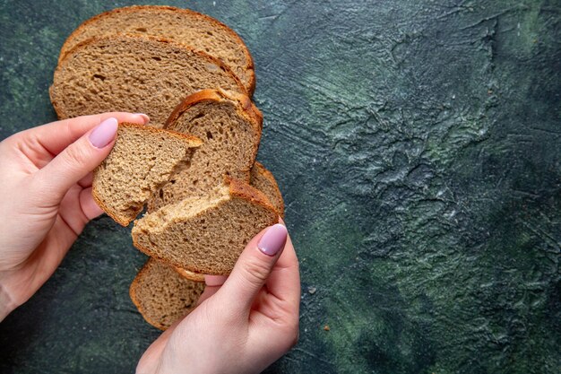 Draufsicht dunkle Brotlaibe mit weiblichem Zerreißen auf dunklem Schreibtisch