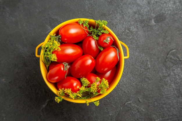 Draufsicht Eimer von Kirschtomaten und Dillblumen auf dem dunklen Hintergrund