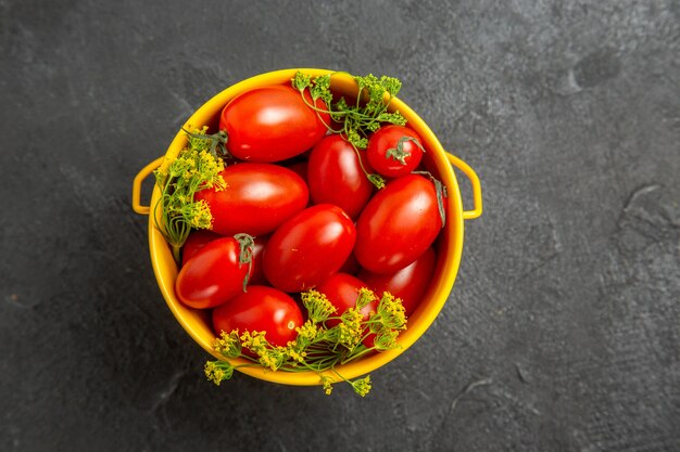 Draufsicht Eimer von Kirschtomaten und Dillblumen auf dem dunklen Hintergrund