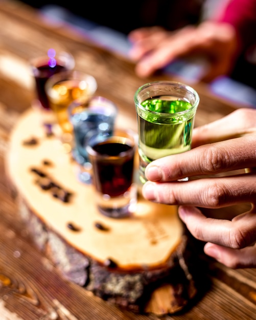 Draufsicht ein Mann trinkt bunte Schüsse mit Kaffeebohnen auf einem Stück Holz