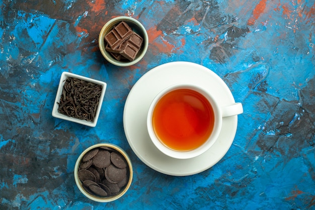 Draufsicht eine Tasse Tee-Pralinen in kleinen Schüsseln auf blauer roter Oberfläche