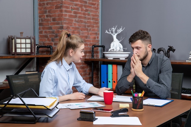 Draufsicht einer jungen Frau, die an einem Tisch sitzt und ihren Kollegen im Büro motiviert