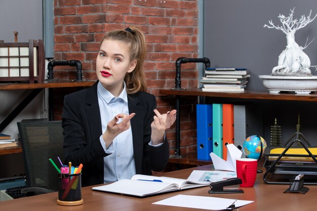 Draufsicht einer jungen Frau, die an einem Tisch sitzt und neugierig auf etwas im Büro ist