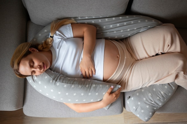 Draufsicht einer schwangeren Frau, die ein Stillkissen verwendet