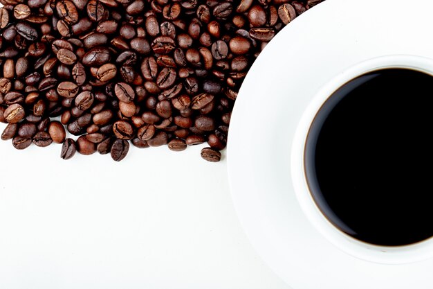 Draufsicht einer Tasse Kaffee mit Kaffeebohnen auf weißem Hintergrund mit Kopienraum