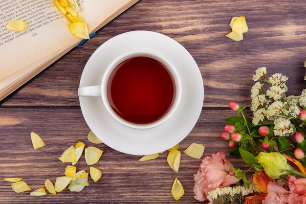 Draufsicht einer Tasse Tee mit gelben Blütenblättern der Blumen auf Holz