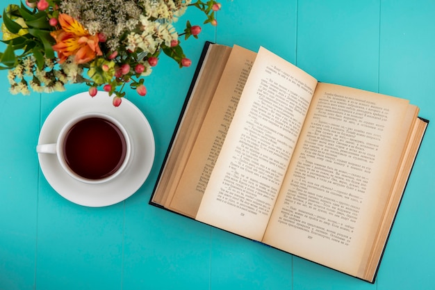 Draufsicht einer Tasse Tee mit schönen Blumen mit Blättern auf Blau