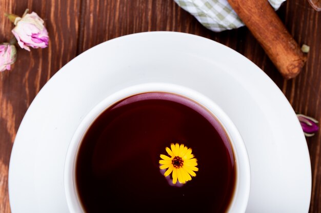 Draufsicht einer Tasse Tee verziert mit Löwenzahnblume auf Holz