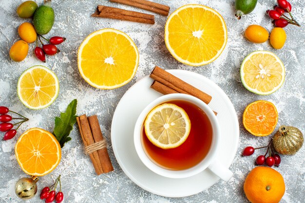 Draufsicht einer Tasse Tee Zitronen-Zimt-Sticks Feijoas auf grauem Hintergrund