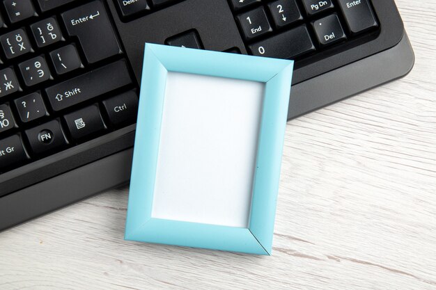 Draufsicht eines blauen leeren Bilderrahmens auf einem halben Laptop auf Weiß