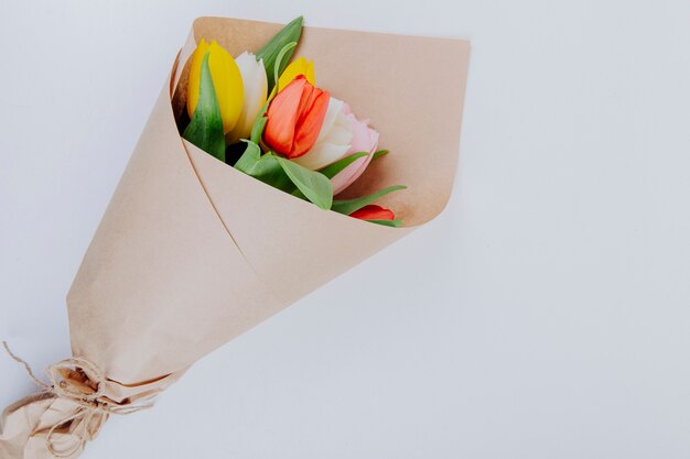 Draufsicht eines Blumenstraußes der bunten Tulpenblumen in einem Bastelpapier auf weißem Hintergrund mit Kopienraum