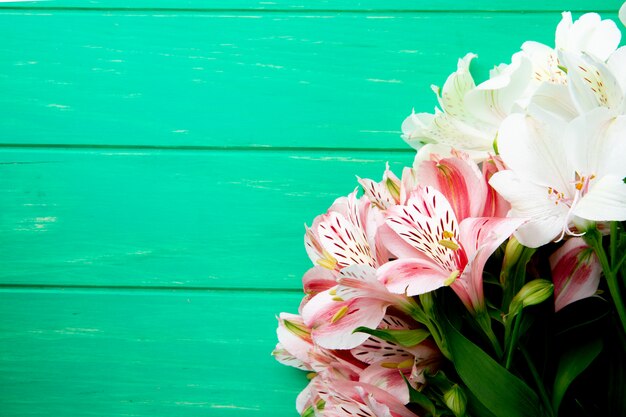 Draufsicht eines Blumenstraußes der rosa und weißen Farbe alstroemeria Blumen, die lokalisiert auf grünem hölzernem Hintergrund mit Kopienraum liegen