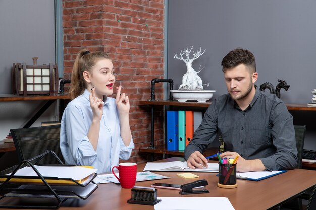 Draufsicht eines jungen Mannes, der sich auf ein Thema konzentriert, während seine Kollegin in der Büroumgebung träumt