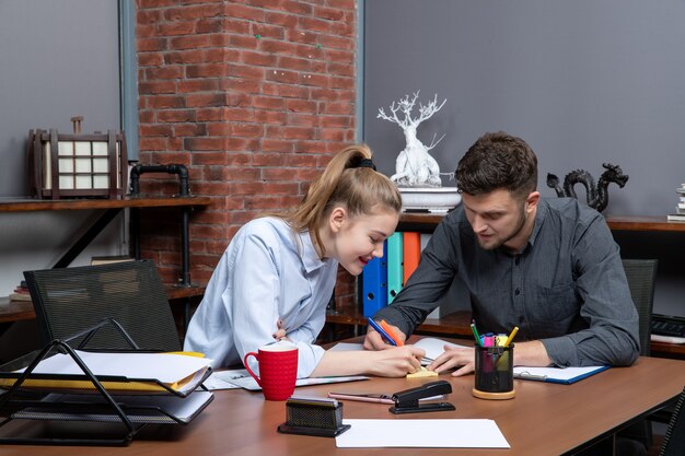 Draufsicht eines jungen motivierten und glücklichen hart arbeitenden Büroteams, das sich auf ein Thema in der Büroumgebung konzentriert