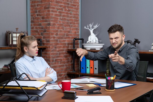 Draufsicht eines jungen verwirrten Büroteams, das am Tisch sitzt und ein wichtiges Thema im Büro diskutiert