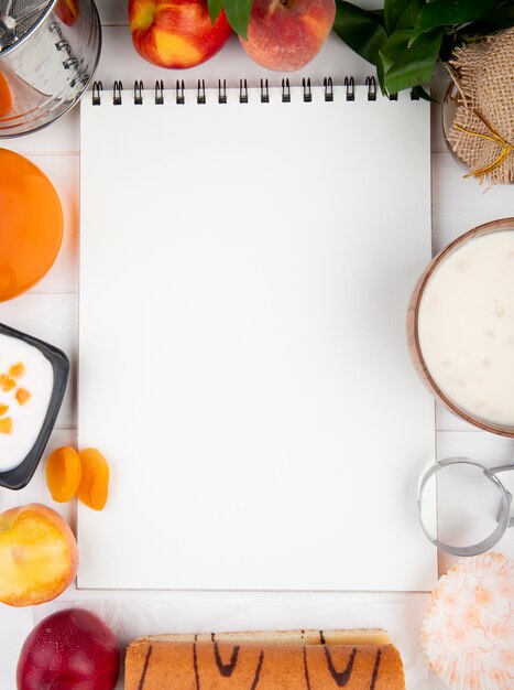 Draufsicht eines Skizzenbuchs mit frischem Pfirsichjoghurt-Hüttenkäse und Marmelade auf Weiß