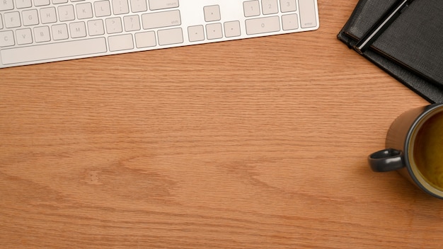 Draufsicht einfacher arbeitsbereich mit tastatur-notebook-kaffeetasse und platz für die montage auf holztisch