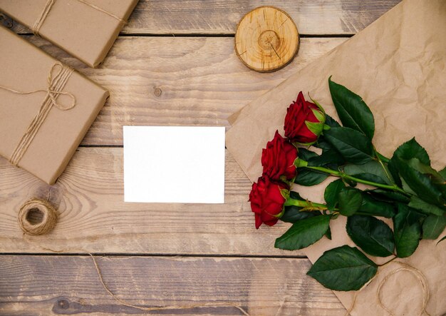 Draufsicht, einladung oder postkarte leerer platz für text. festliche atmosphäre, rote rosen, auf einem hölzernen hintergrund.