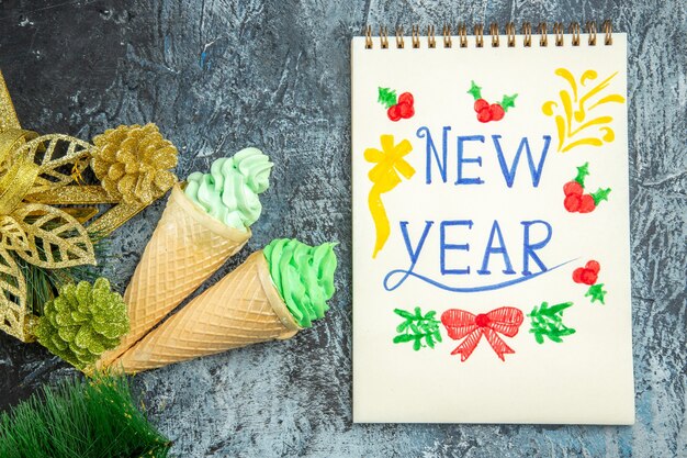 Draufsicht Eiscreme Weihnachtsschmuck neues Jahr auf Notizbuch auf grauem Hintergrund geschrieben