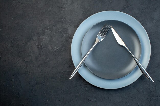 Draufsicht elegante Teller mit Messer und Gabel auf dunklem Hintergrund Hunger Besteck Weiblichkeit buntes Diner