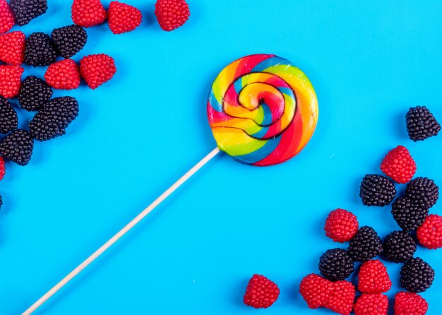 Draufsicht farbiger Eiszapfen mit Marmelade in Form von Himbeeren und Brombeeren auf blauem Grund