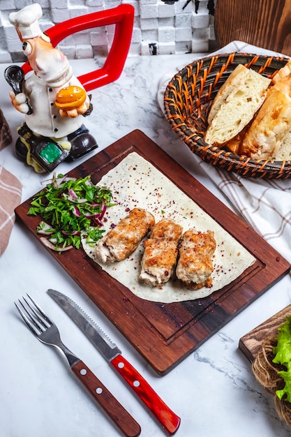 Draufsicht Fleisch Lula Kebab auf Fladenbrot mit Kräutern und Zwiebeln auf einem Brett