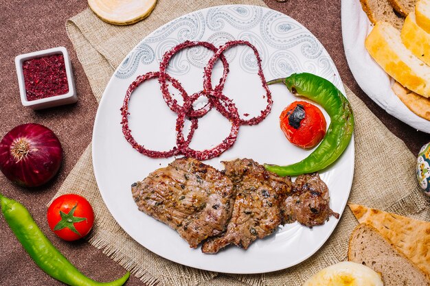 Draufsicht Fleischbasturma-Kebab mit Tomate und Paprika auf dem Grill mit Zwiebel im Sumach