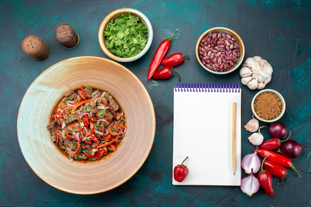 Kostenloses Foto draufsicht fleischige gemüsemahlzeit innerhalb platte zusammen mit grünem paprika bohnengemüse mit notizblock auf dem dunkelblauen schreibtischlebensmittelmahlzeitgemüsewürz