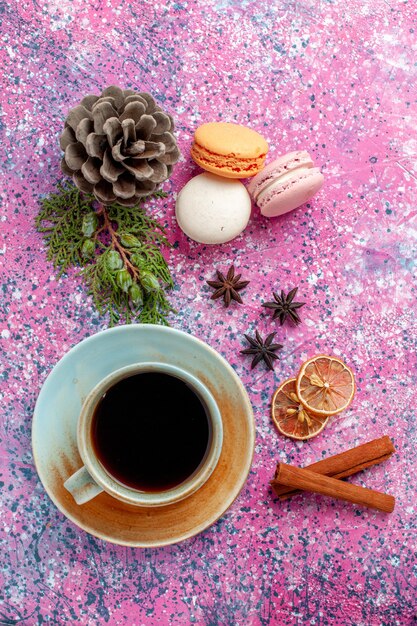 Draufsicht französische Macarons köstliche kleine Kuchen mit Tee auf rosa Oberfläche