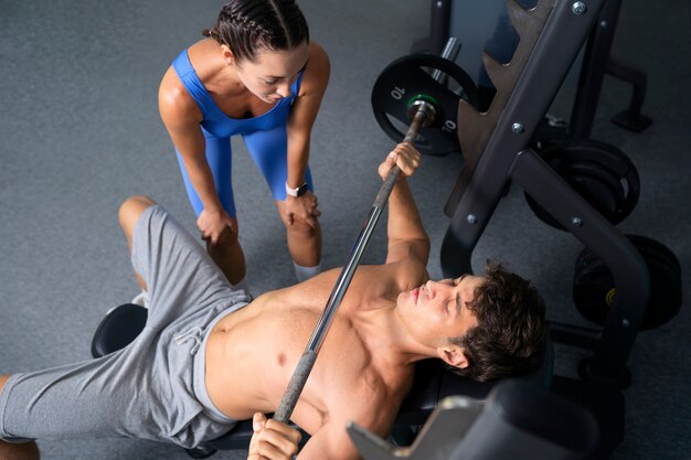 Draufsicht Frau hilft Mann im Fitnessstudio