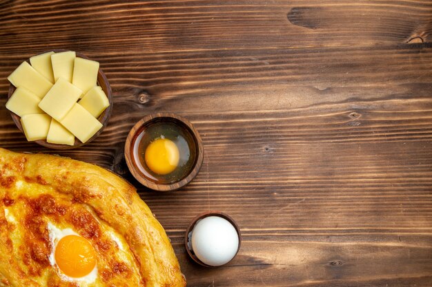 Draufsicht frisch gebackenes Brot mit gekochtem Ei auf braunem Schreibtisch Brotteig Mahlzeit Brötchen Frühstücksei Essen