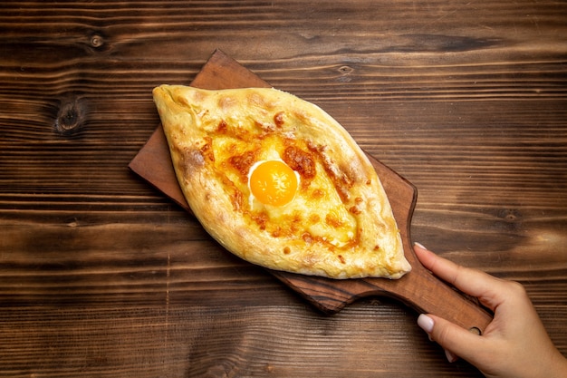 Draufsicht frisch gebackenes Brot mit gekochtem Ei auf hölzernem Schreibtisch Brotteigbrötchen-Lebensmittelfrühstücksei