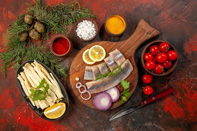 Draufsicht frisch geschnittener Fisch mit Gewürzen Tomaten und Käse auf dunklem Hintergrund