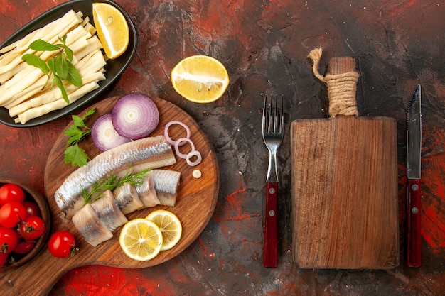 Draufsicht frisch geschnittener Fisch mit Zwiebelringen und frischen Tomaten auf dunklem Hintergrund