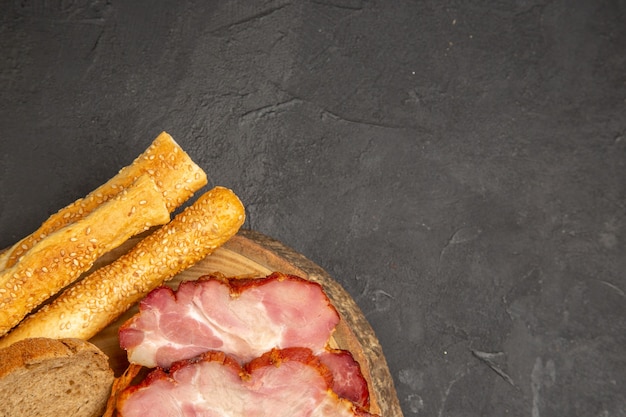 Kostenloses Foto draufsicht frisch geschnittener schinken mit brötchen und brotscheiben auf dunklem hintergrund