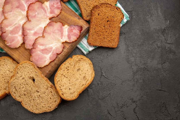 Draufsicht frisch geschnittener Schinken mit Gewürzen und Brot auf dunklem Hintergrund