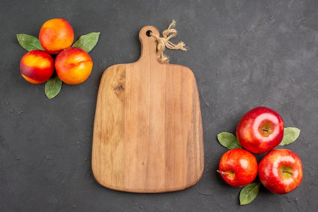 Kostenloses Foto draufsicht frische äpfel mit pfirsichen auf der dunklen tischfarbe frisches obst reif