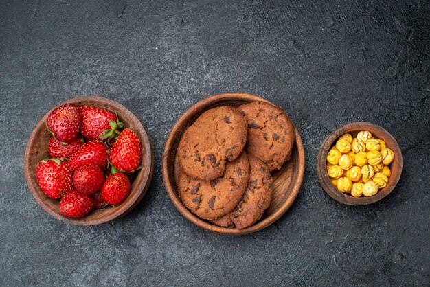 Draufsicht frische Erdbeeren mit Keksen auf dunklem Tisch süßes Fruchtplätzchen