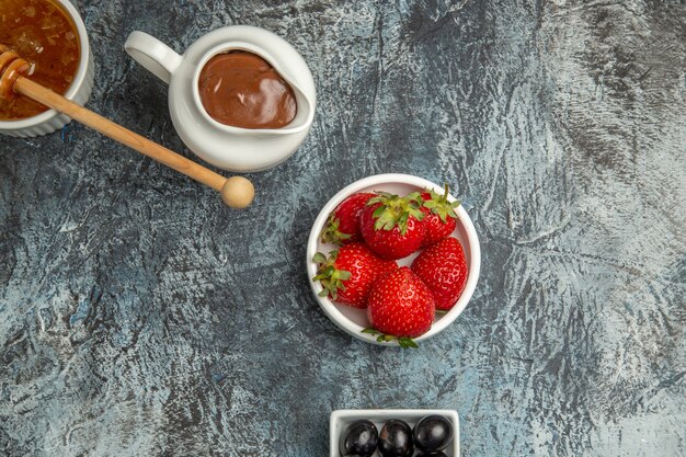 Draufsicht frische Erdbeeren mit Oliven und Honig auf dunkler Oberfläche süße Fruchtbeere