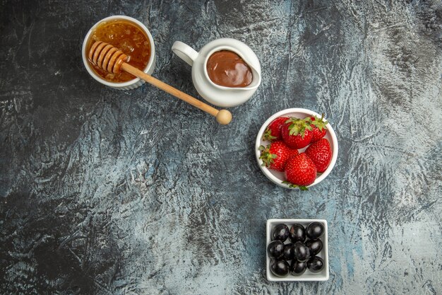 Draufsicht frische Erdbeeren mit Oliven und Honig auf dunkler Oberfläche süße Fruchtbeere