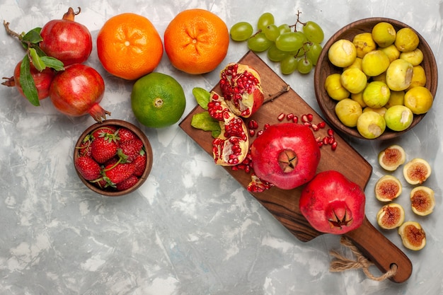 Kostenloses Foto draufsicht frische feigen mit granatäpfeln und trauben auf weißem schreibtisch